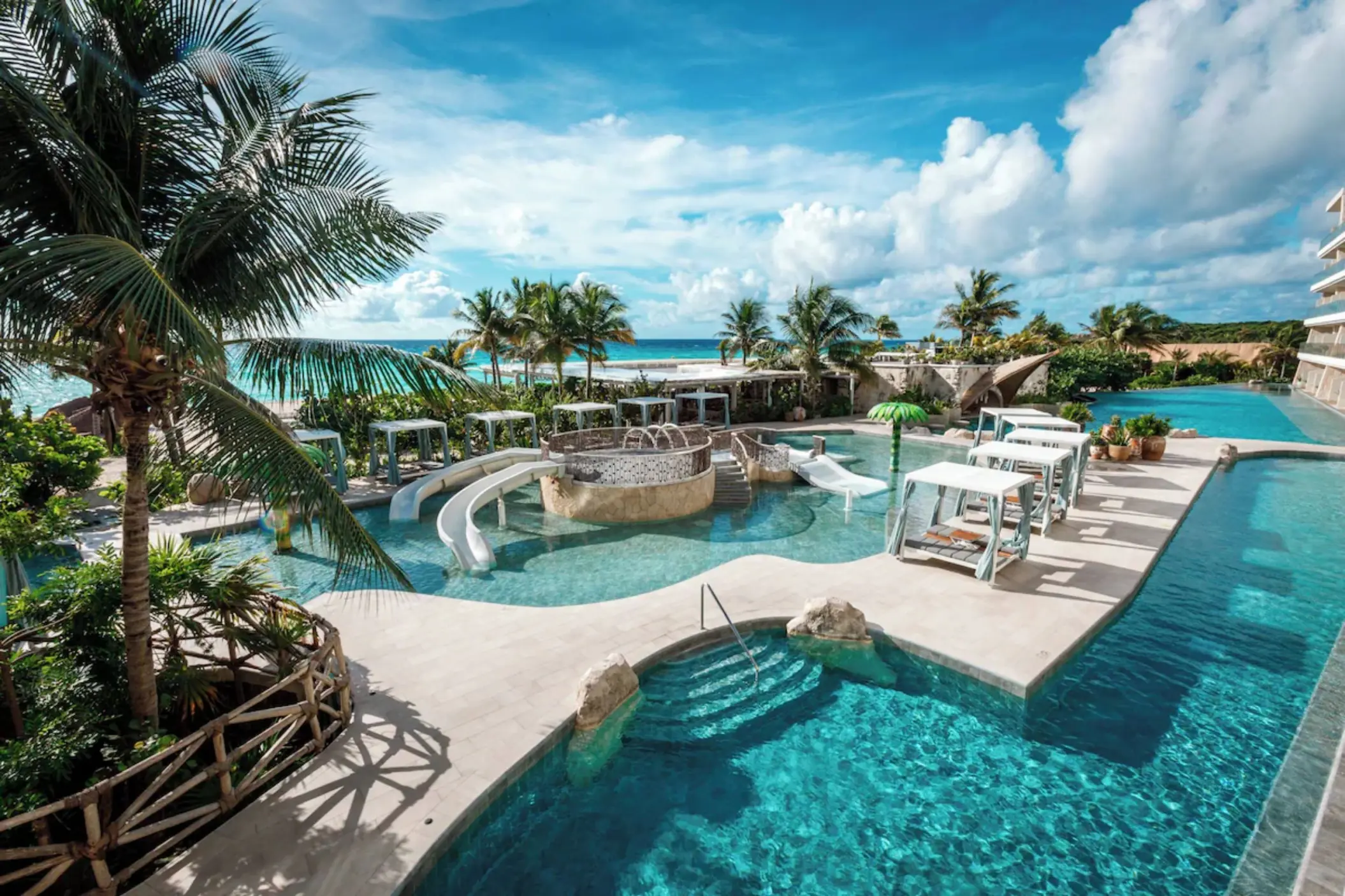 Multi-level outdoor swimming pools surrounded by tropical greenery at Palmaïa – The House of AïA in Riviera Maya