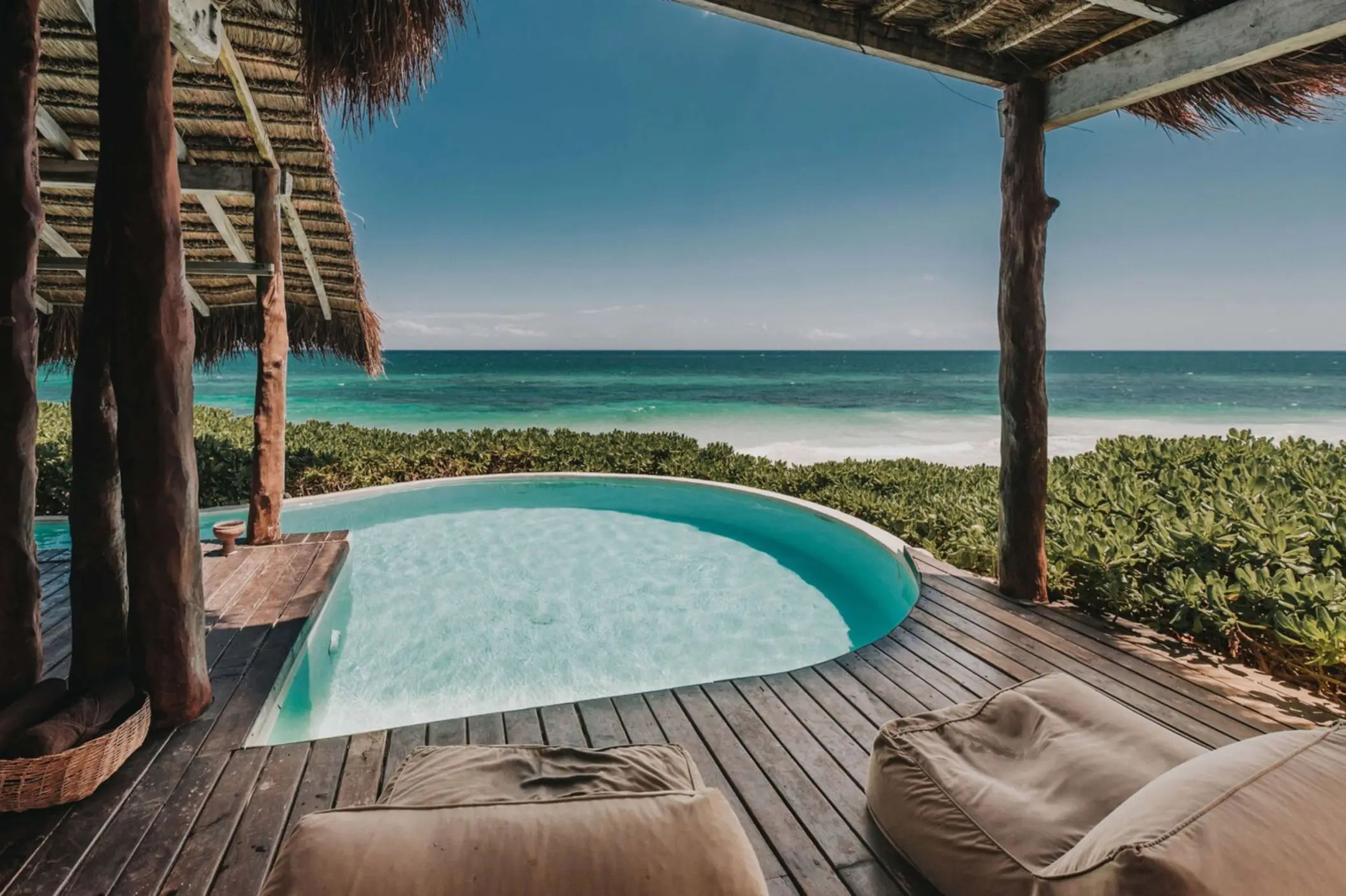 A private plunge pool set on a wooden deck, part of a Casa Palapa, offering direct ocean views and surrounded by tropical plants.