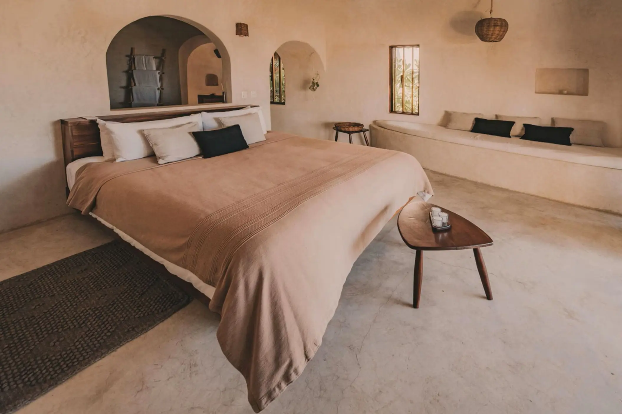 A spacious casita interior with a king-sized bed, minimalistic decor, smooth stucco walls, and wooden furniture.