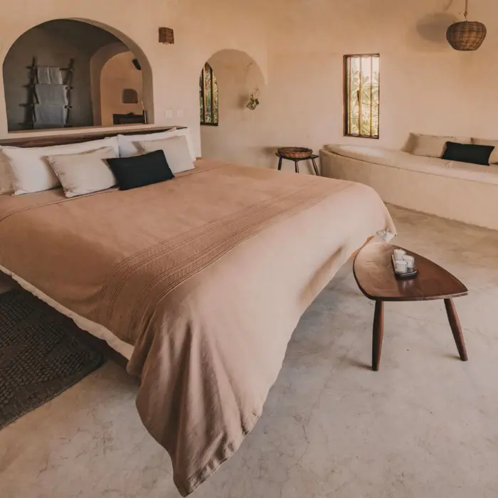 A spacious casita interior with a king-sized bed, minimalistic decor, smooth stucco walls, and wooden furniture.