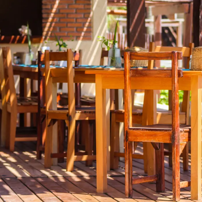 Outdoor dining area of Restaurant Molcajete at Piedra Escondida with wooden tables and chairs on a shaded deck.
