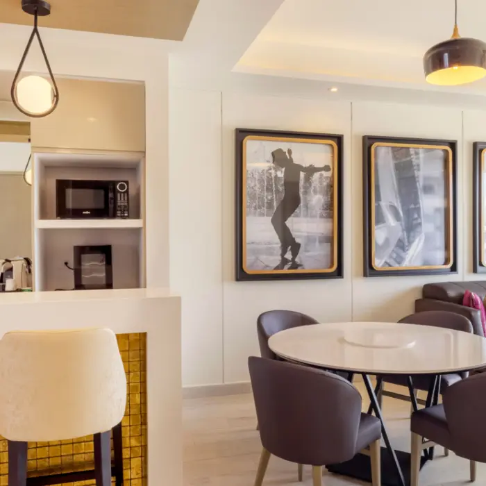 Bright suite interior with stylish furniture, bar counter, and framed black-and-white cinema art.