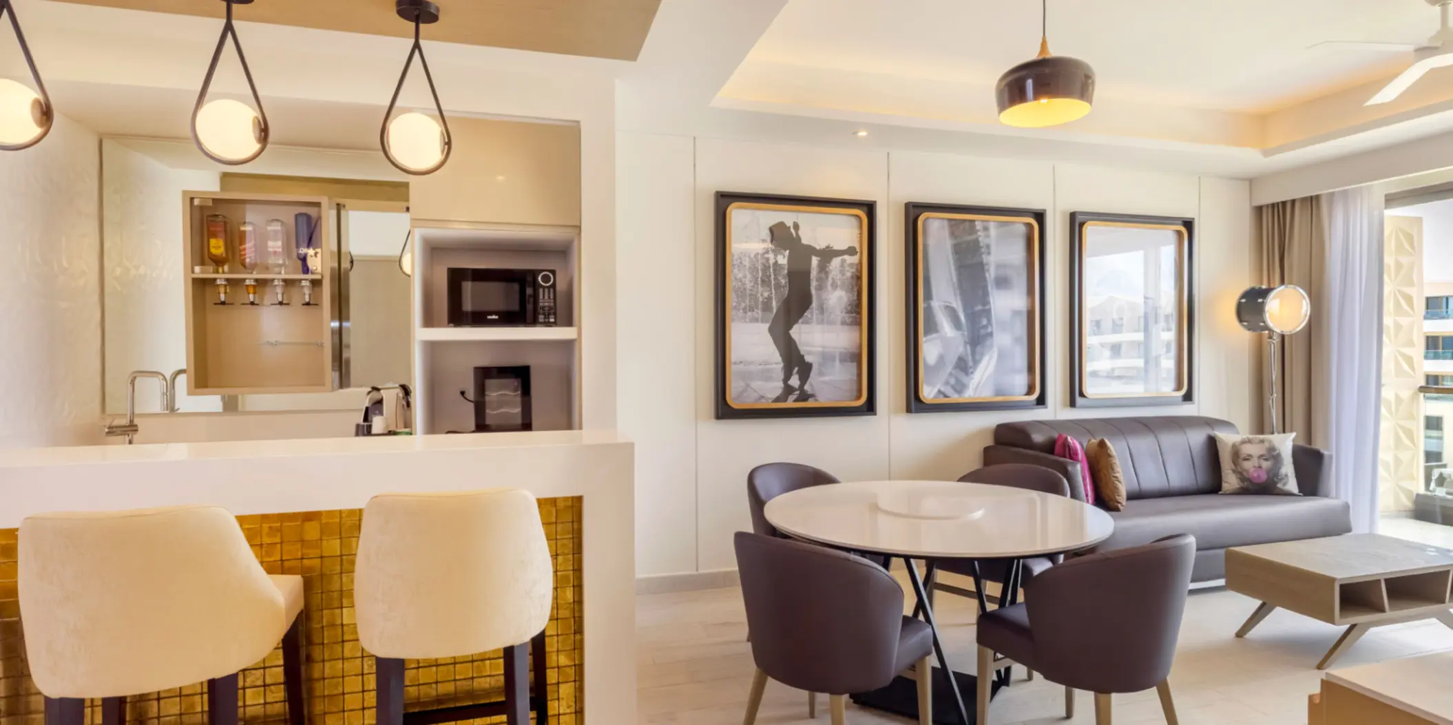 Bright suite interior with stylish furniture, bar counter, and framed black-and-white cinema art.