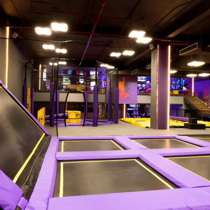 Indoor trampoline park with purple padding, climbing features, and vibrant lighting for active play.