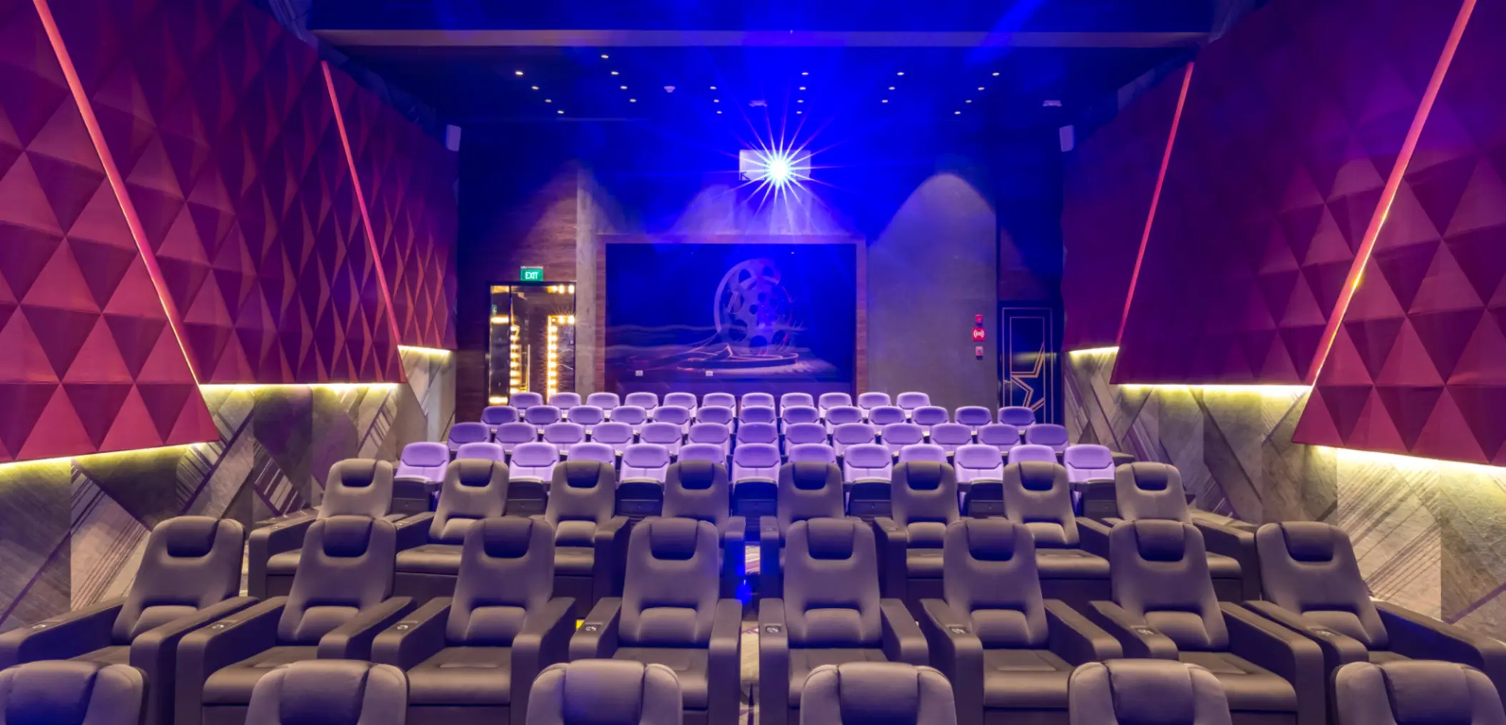 Private cinema room with plush reclining seats and glowing blue light shining from the projector.