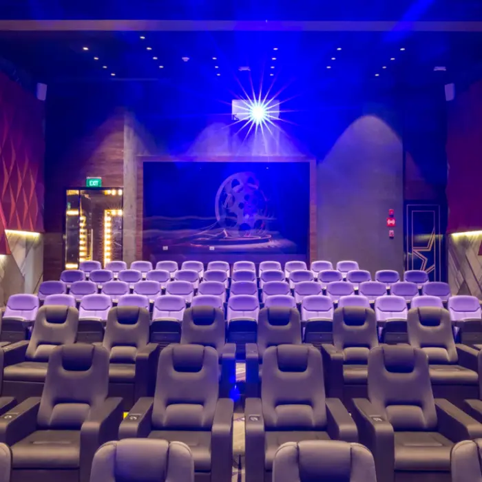 Private cinema room with plush reclining seats and glowing blue light shining from the projector.
