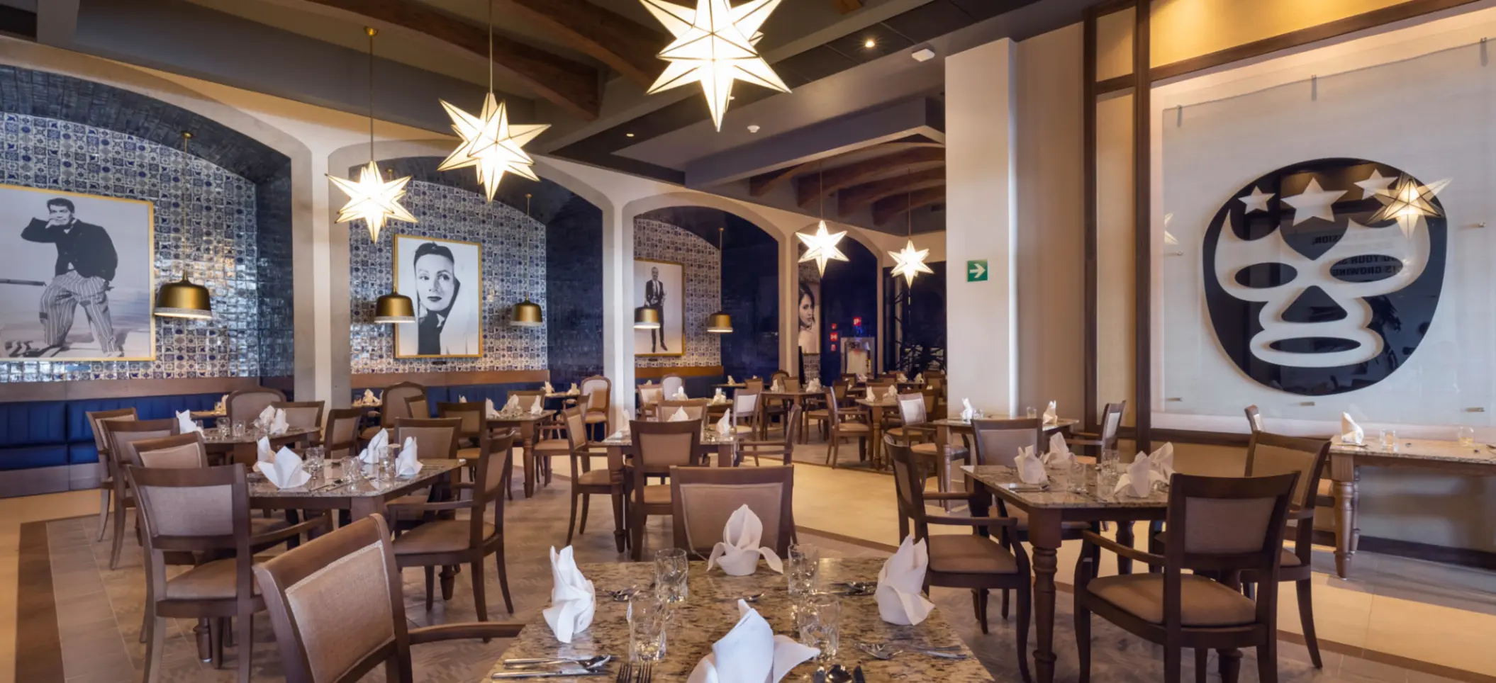 Mexican-themed restaurant with blue tile walls, portraits of classic stars, and glowing star-shaped lights.