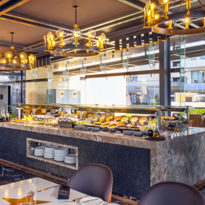 Upscale buffet restaurant with marble counters, modern lighting, and a variety of fresh dishes on display.