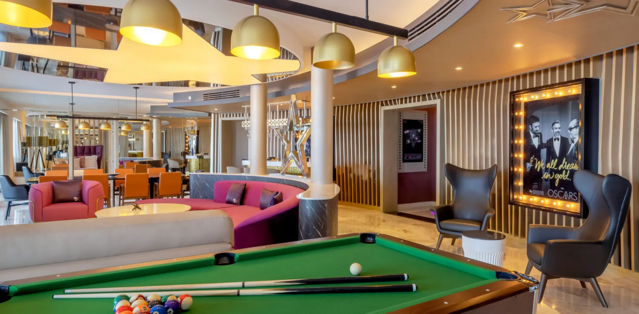 Stylish entertainment lounge with billiards, plush seating, Oscar-themed decor, and a cozy, cinematic ambiance.