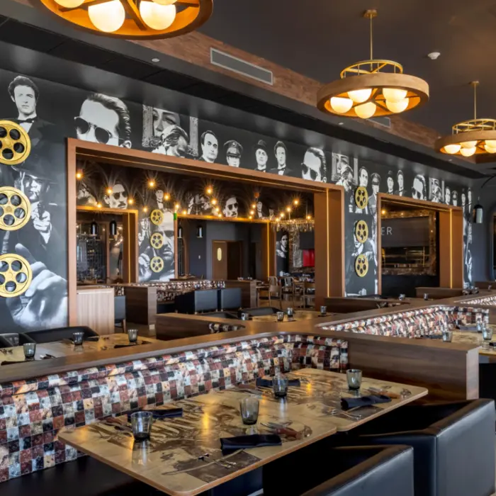 Cinematic-themed restaurant with black-and-white movie star mural, film reels, and cozy booth seating.