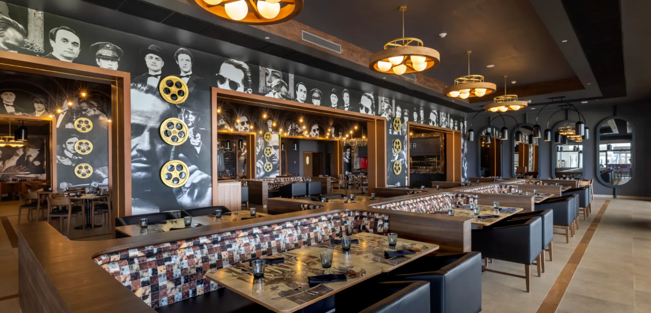 Cinematic-themed restaurant with black-and-white movie star mural, film reels, and cozy booth seating.