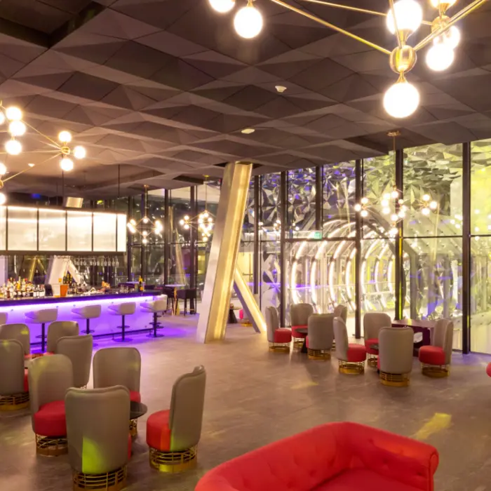 Stylish cocktail bar with purple lighting, plush seating, and geometric wall décor for a modern vibe.