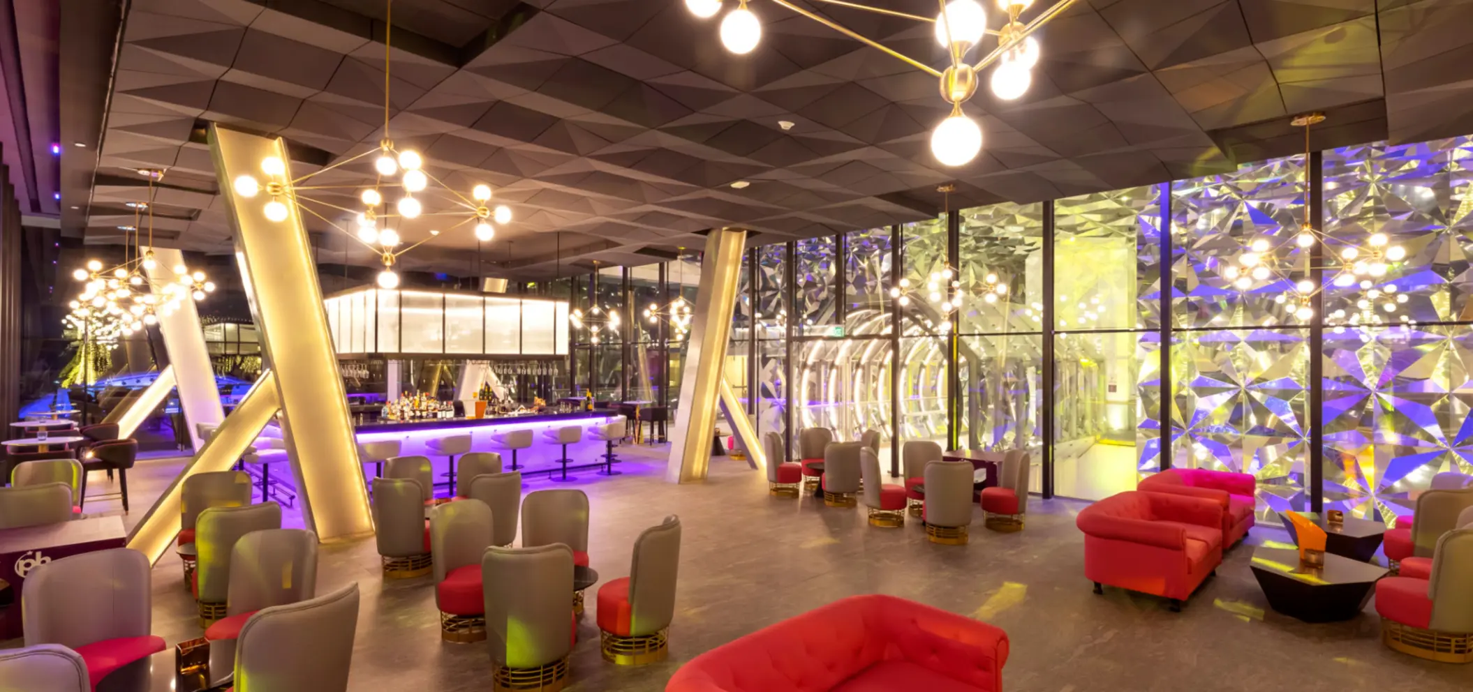 Stylish cocktail bar with purple lighting, plush seating, and geometric wall décor for a modern vibe.