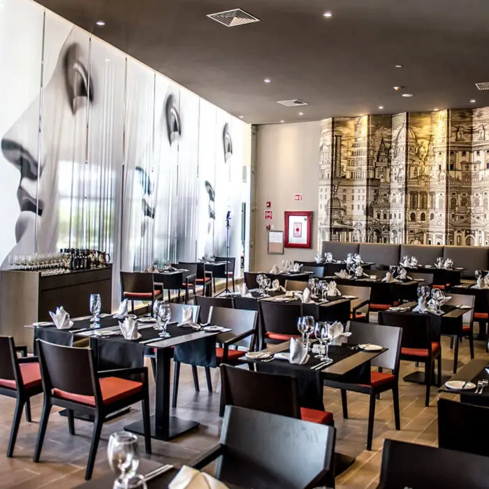 Interior of the Bruschetta restaurant with modern decor, set tables, and distinctive murals on the walls.