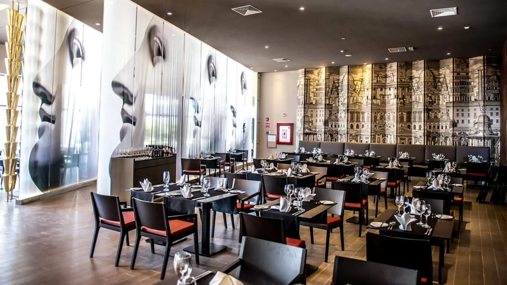 Interior of the Bruschetta restaurant with modern decor, set tables, and distinctive murals on the walls.