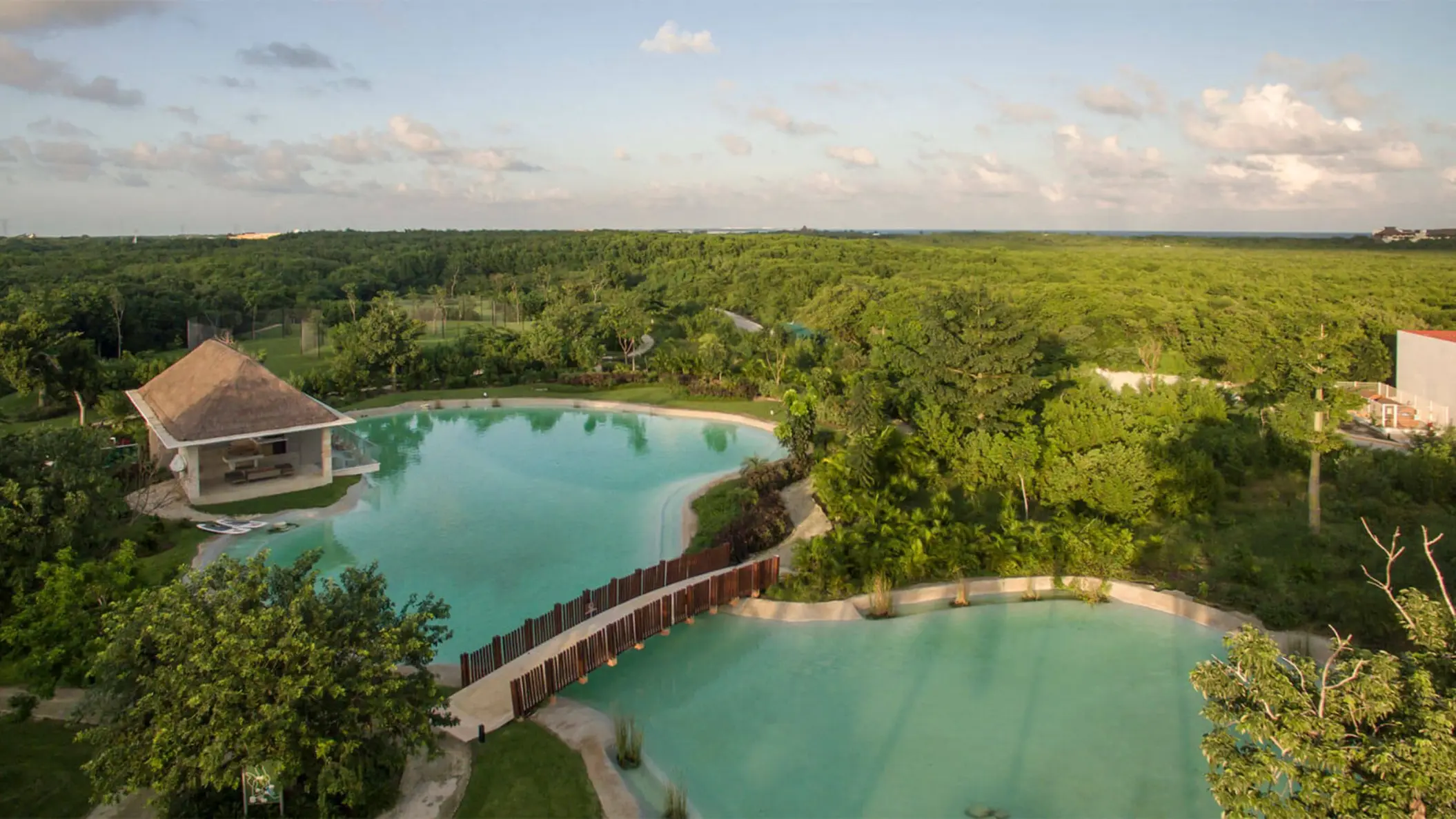 Aerial view of cenote-style pools surrounded by lush green jungle at the Platinum Yucatan Princess resort.