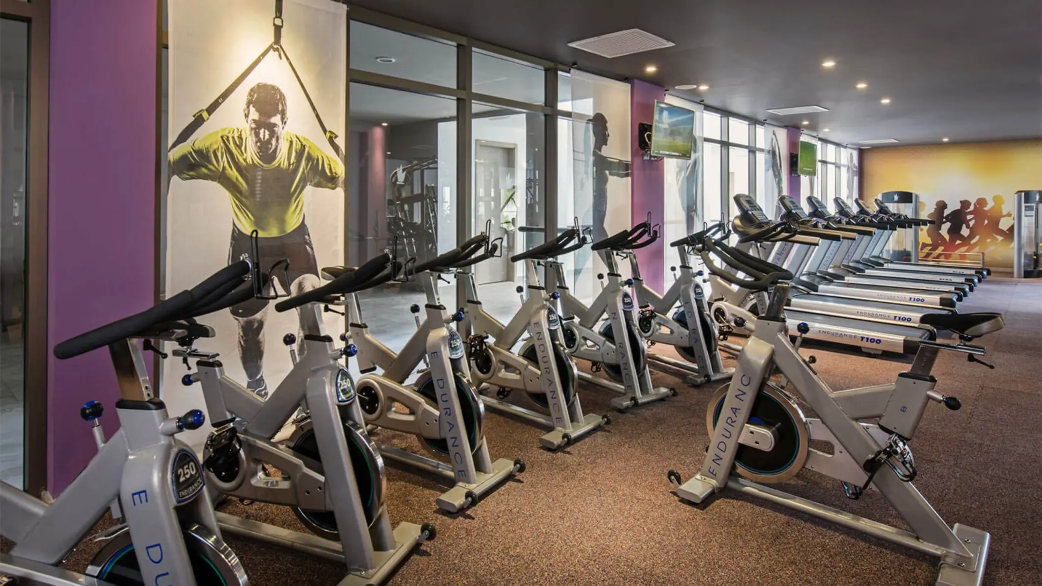 The hotel gym with a row of stationary bikes, treadmills, and mirrored walls.