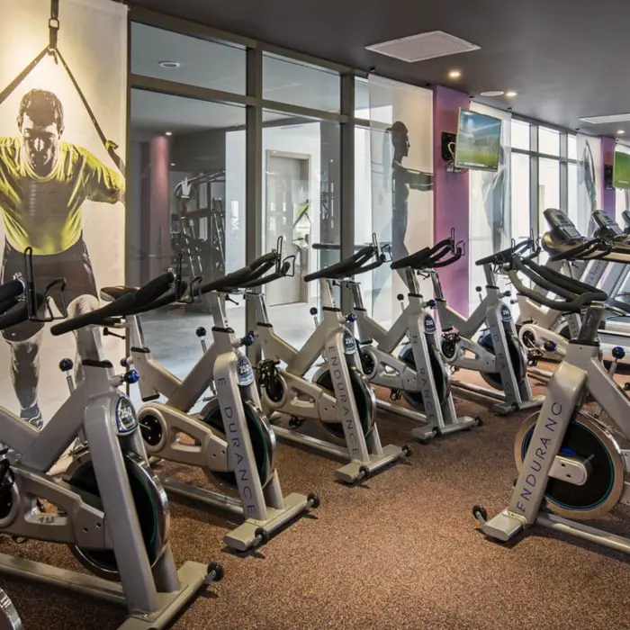 The hotel gym with a row of stationary bikes, treadmills, and mirrored walls.