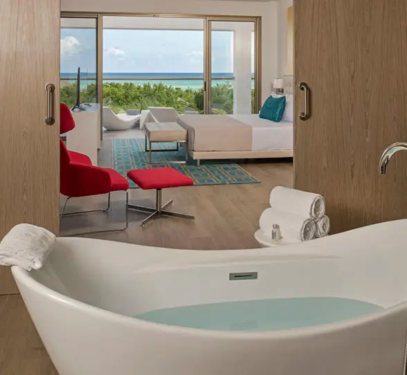 A Master Suite featuring a standalone bathtub in the foreground and the bedroom area visible through sliding wooden doors.