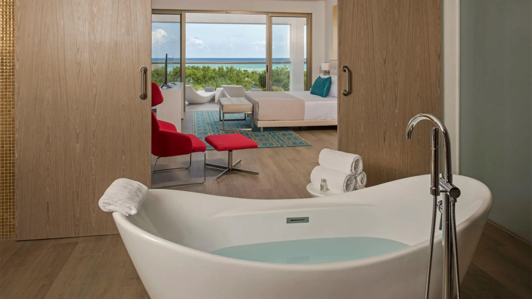 A Master Suite featuring a standalone bathtub in the foreground and the bedroom area visible through sliding wooden doors.