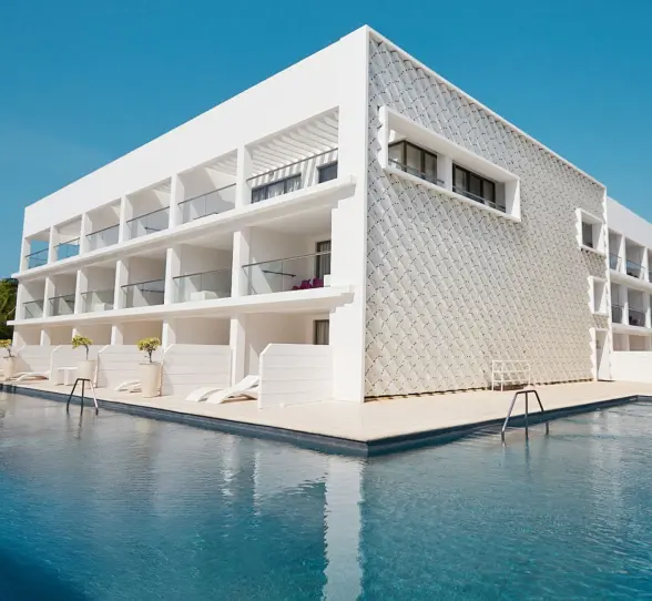 Exterior view of the hotel building overlooking a large pool, with contemporary white architecture and glass balconies.