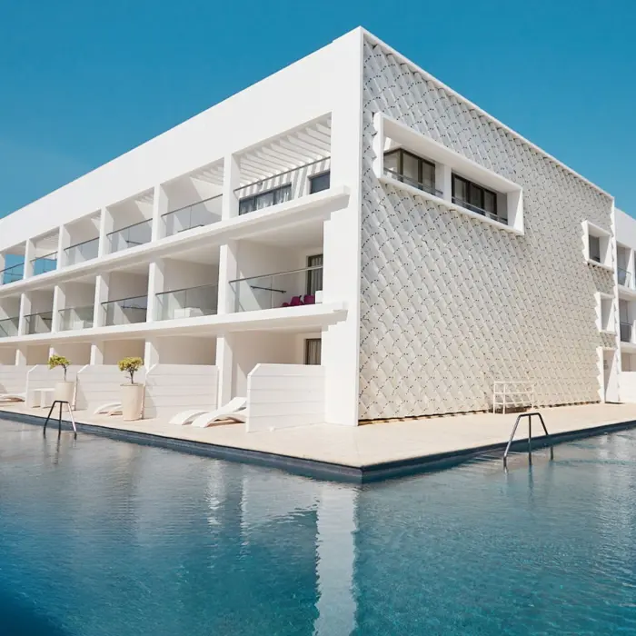 Exterior view of the hotel building overlooking a large pool, with contemporary white architecture and glass balconies.