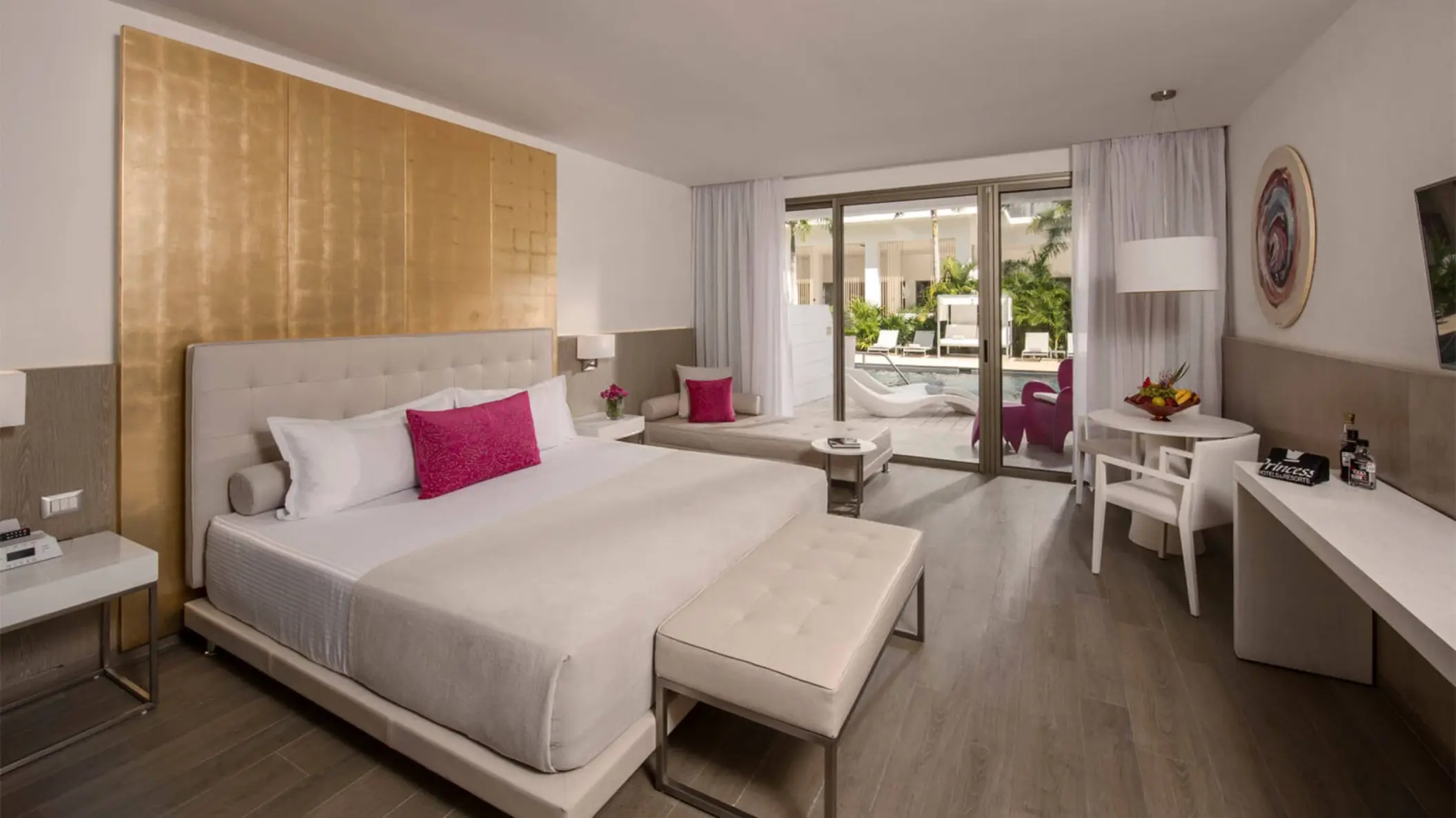 Interior of a swim-up suite with a king bed, modern decor, and direct access to the pool area through a glass door.