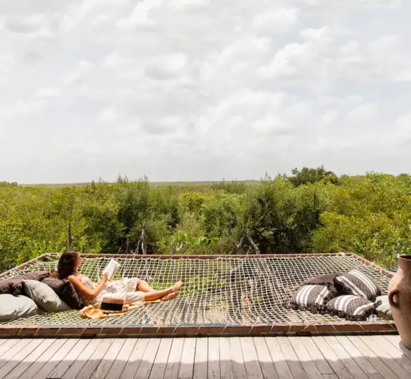 Relaxing hammock net on terrace at Radhoo Tulum, surrounded by jungle views and boho-style decor.
