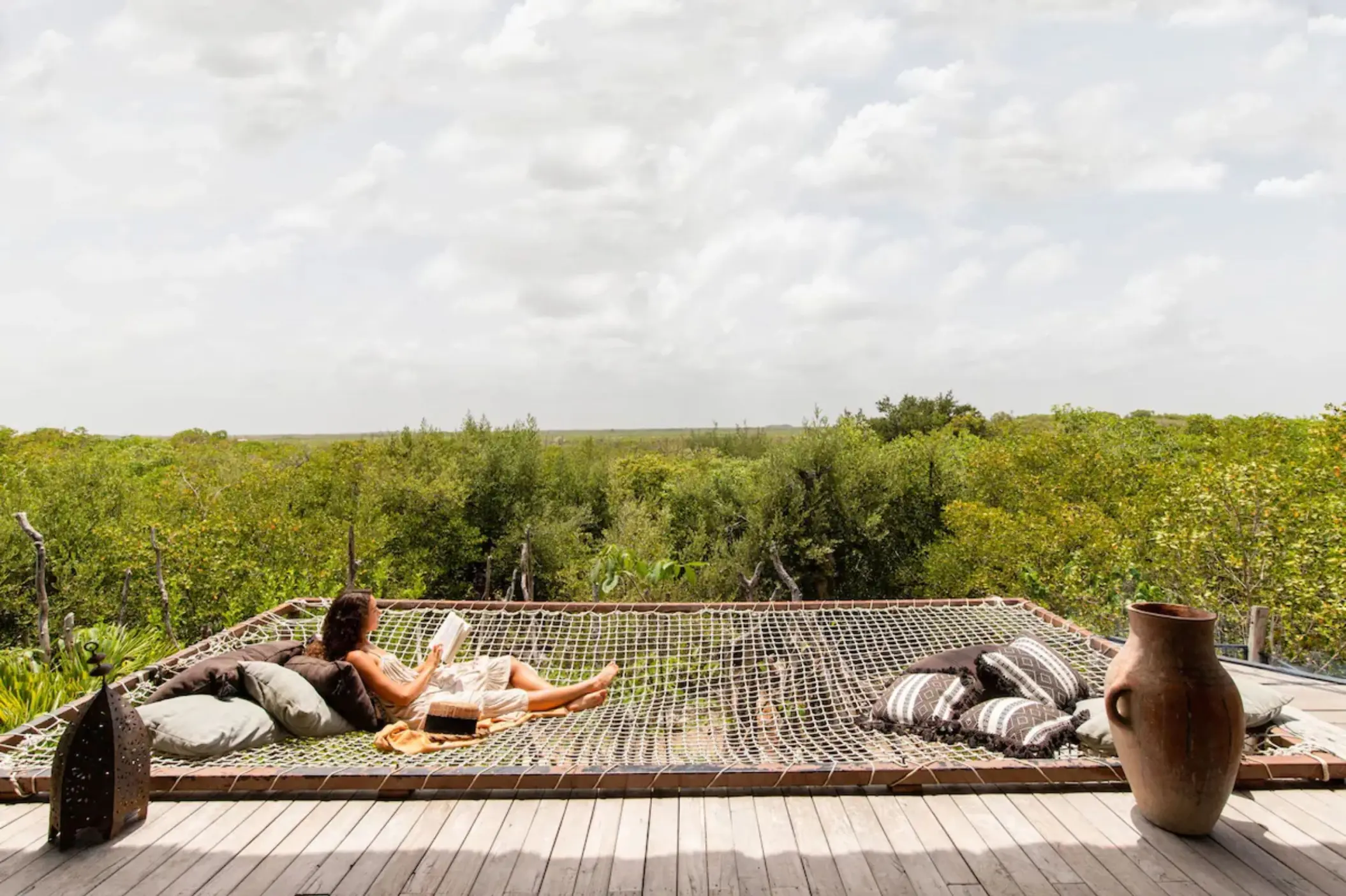 Relaxing hammock net on terrace at Radhoo Tulum, surrounded by jungle views and boho-style decor.