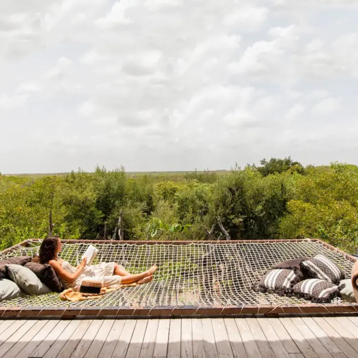 Relaxing hammock net on terrace at Radhoo Tulum, surrounded by jungle views and boho-style decor.