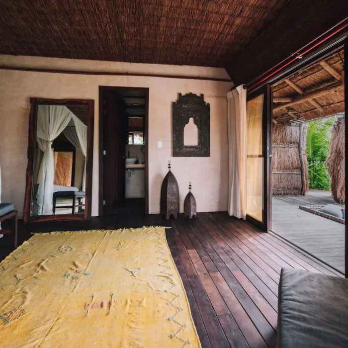 Cozy suite at Radhoo Tulum with earthy tones, wooden accents, and soft linens for a serene jungle escape.