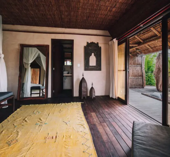 Cozy suite at Radhoo Tulum with earthy tones, wooden accents, and soft linens for a serene jungle escape.