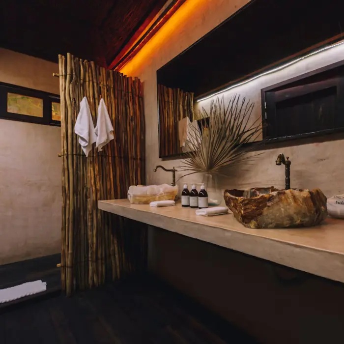 Artisanal stone washbasin at Radhoo Tulum with eco-friendly toiletries and minimal jungle-inspired decor.