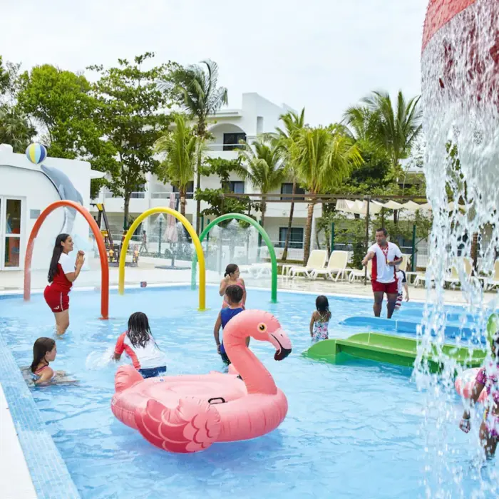 A vibrant kids' water park with slides, water features, and a large pink flamingo float in a pool.