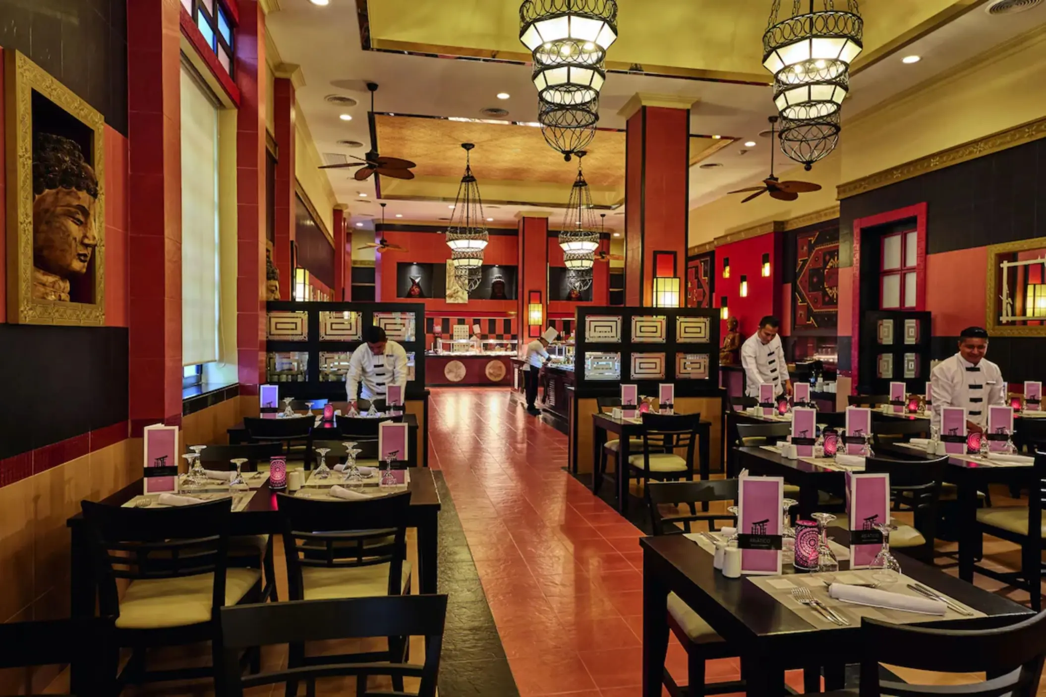 An Asian restaurant with a sushi bar, red and black decor, and tables set for dining.