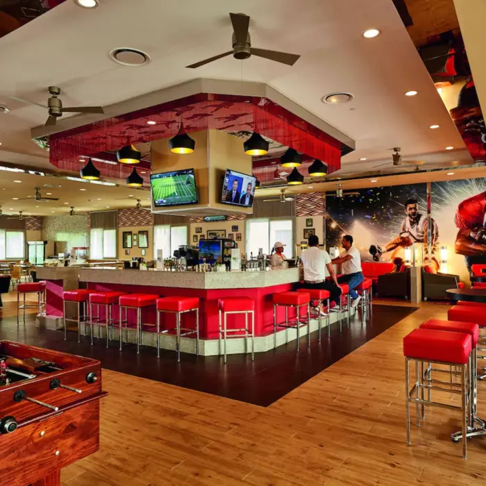 A sports bar with multiple TVs, a large counter, and lounge-style seating.