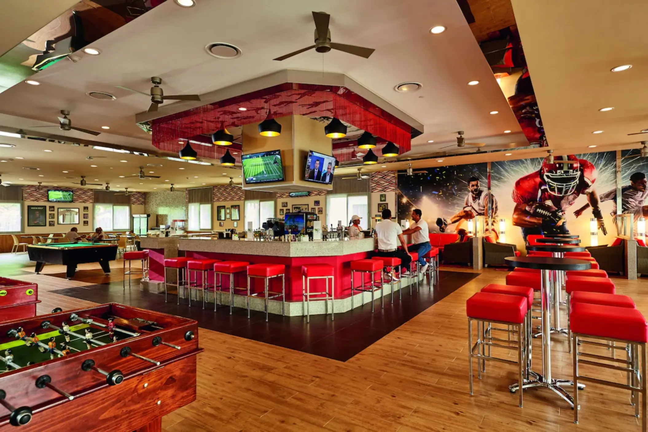 A sports bar with multiple TVs, a large counter, and lounge-style seating.