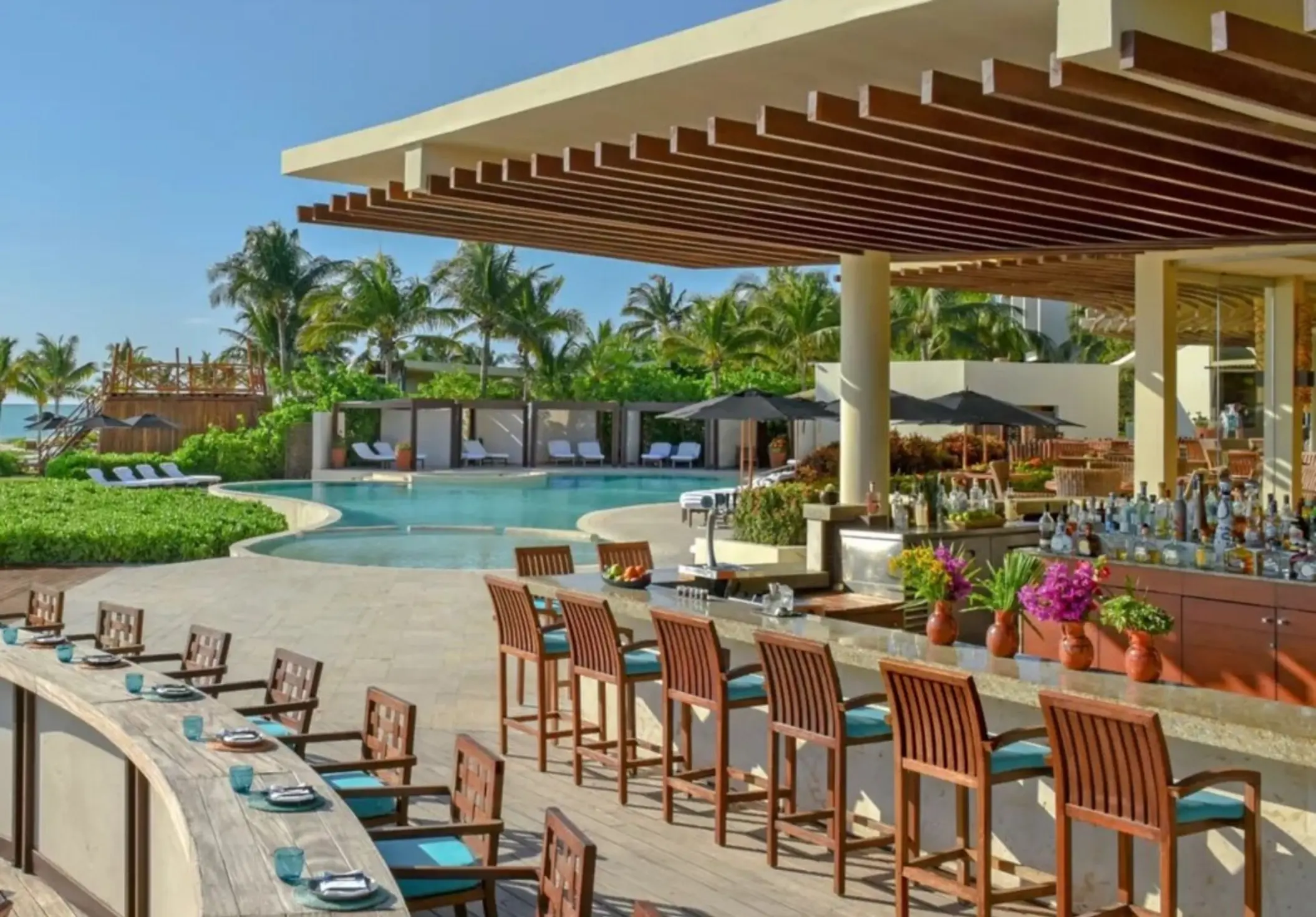 Outdoor poolside bar at Rosewood Mayakoba with ocean views, tropical landscaping, and swim-up seating