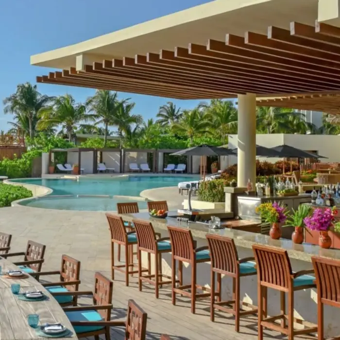 Outdoor poolside bar at Rosewood Mayakoba with ocean views, tropical landscaping, and swim-up seating