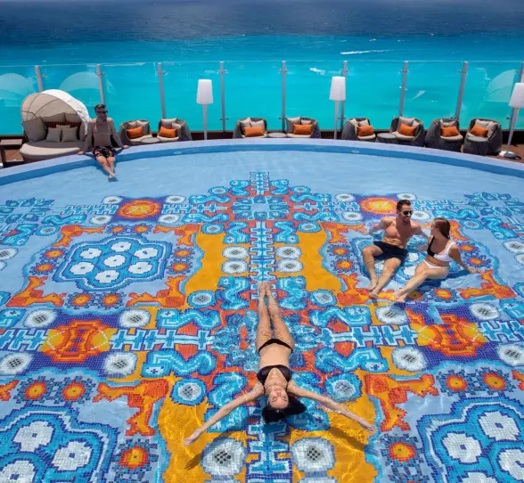 people lounging in and around the rooftop pool at Royalton CHIC Cancun