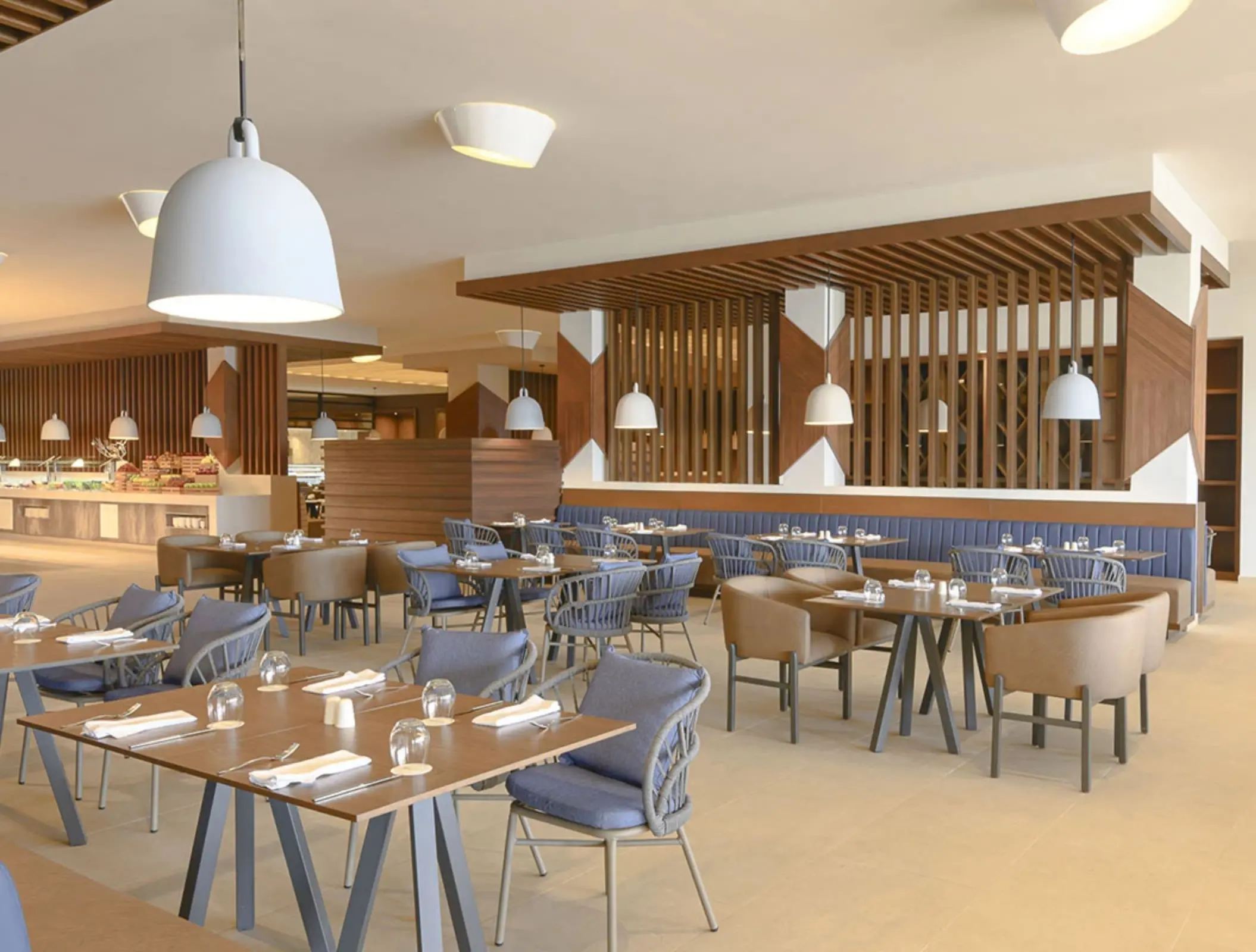 Bright buffet-style restaurant with wooden decor, pendant lights, and comfortable modern dining furniture.