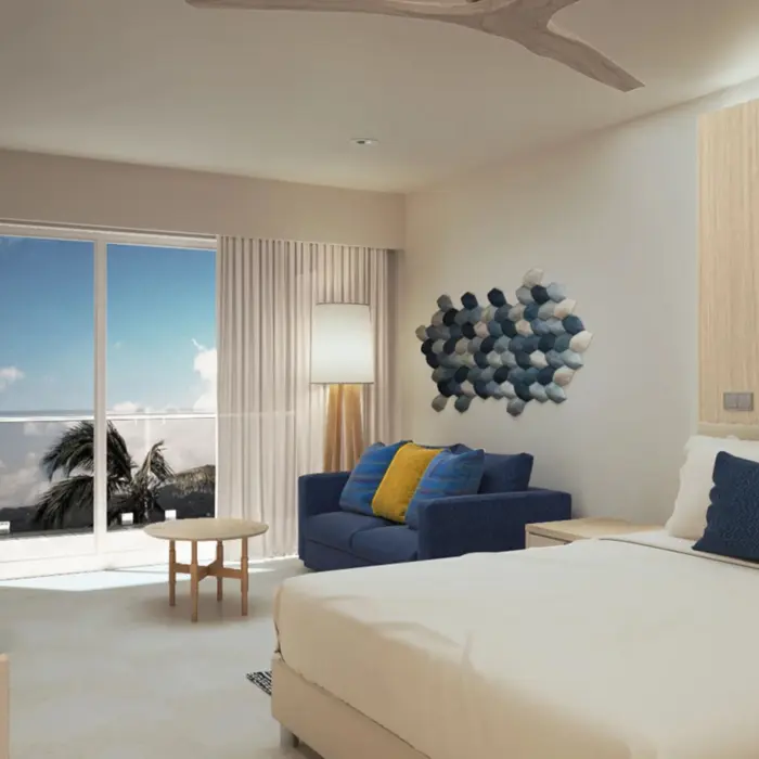 Bright and modern oceanview hotel suite with balcony, seating area, and coastal-inspired wall art.