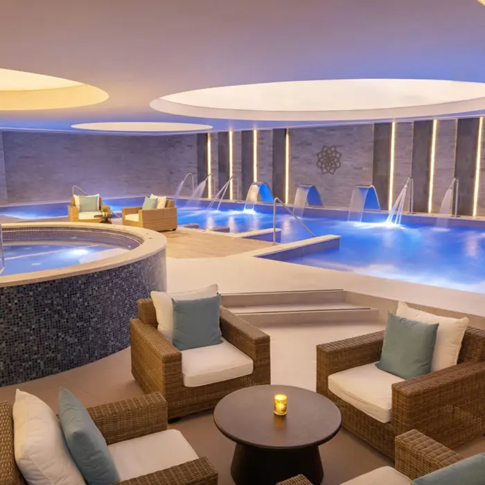 Spa hydrotherapy area with loungers, whirlpools, warm lighting, and water jets in a tranquil indoor space.