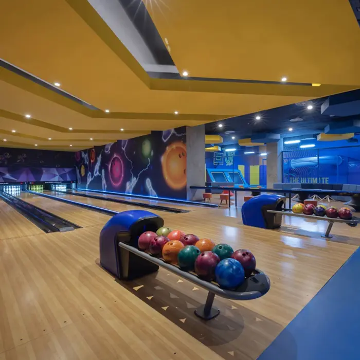 Bright, colorful bowling alley with two lanes, cosmic-themed decor, and bowling balls ready for play.