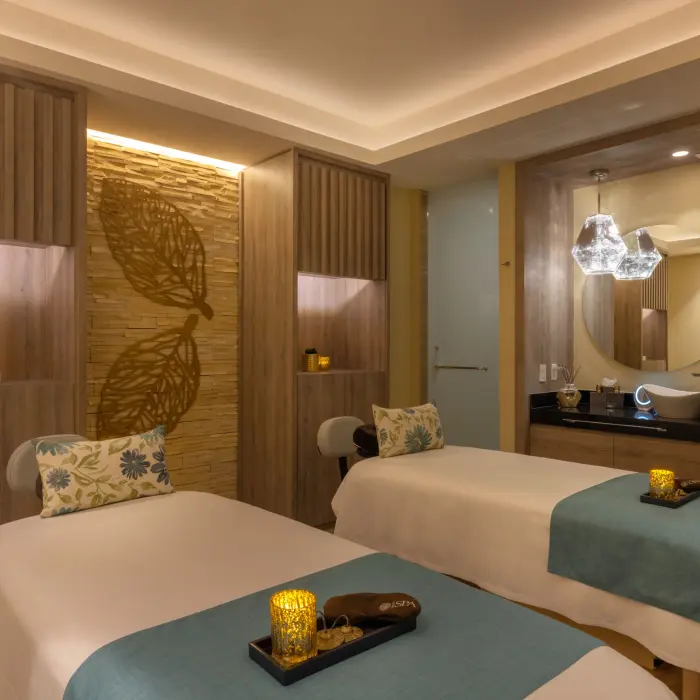 Tranquil spa treatment room with dual massage beds, soft lighting, and relaxing earth-toned design elements.