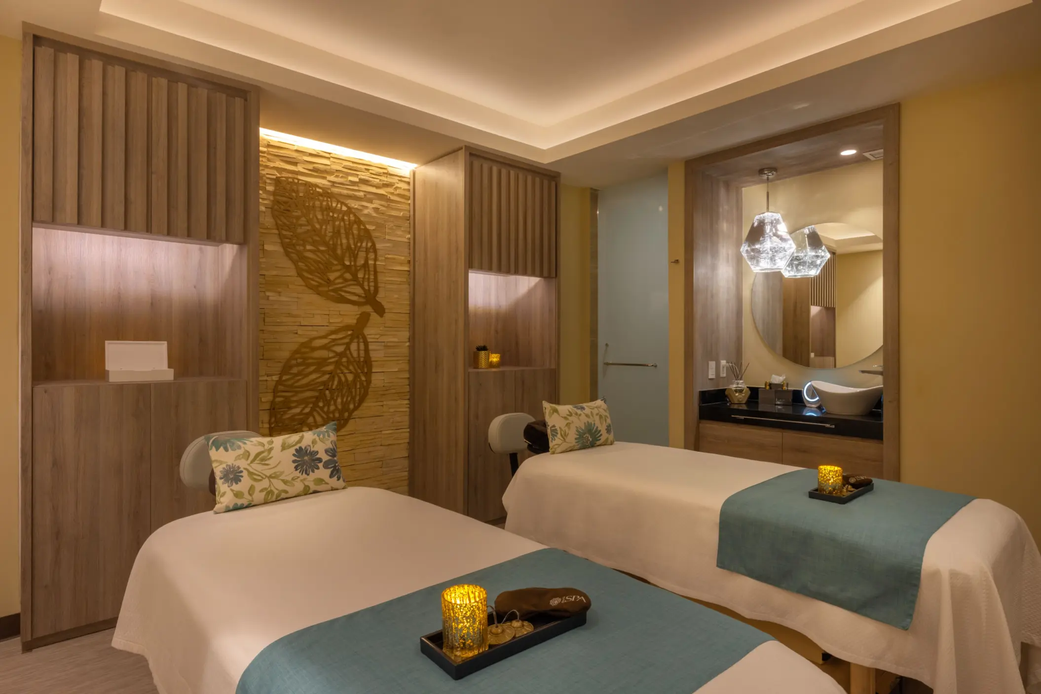 Tranquil spa treatment room with dual massage beds, soft lighting, and relaxing earth-toned design elements.