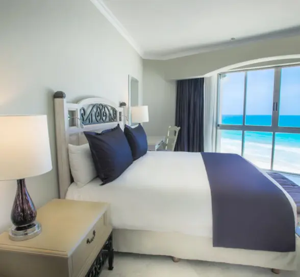 Bedroom with a king-sized bed and a large window offering a panoramic view of the turquoise ocean.