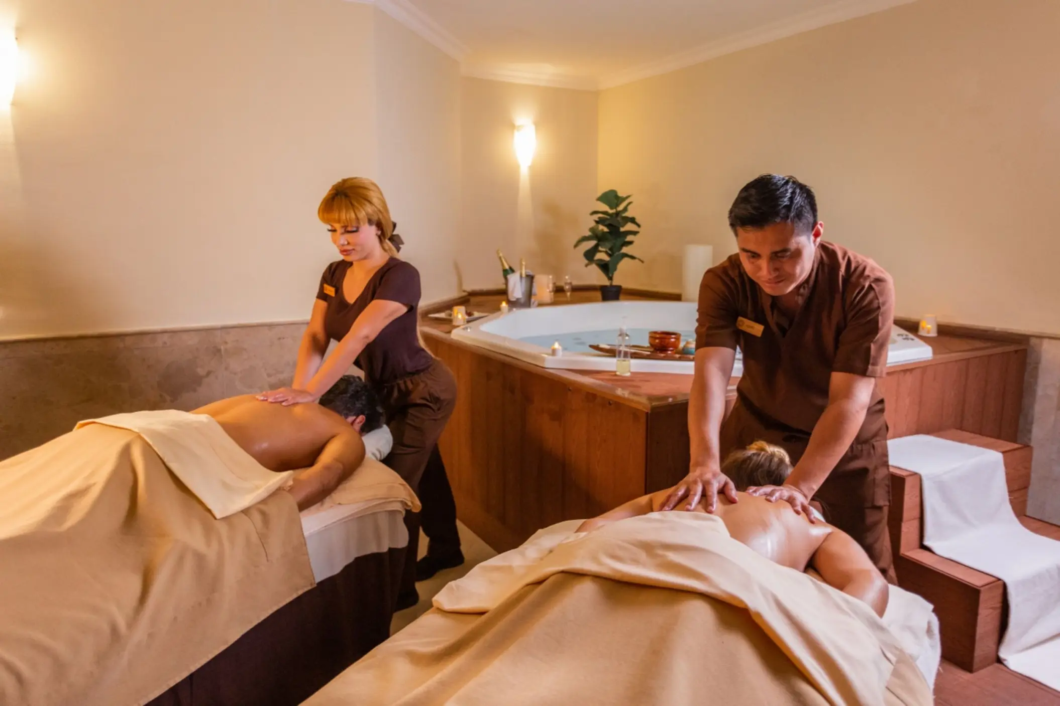 A couple receiving a relaxing massage side-by-side in a tranquil, dimly lit spa room.