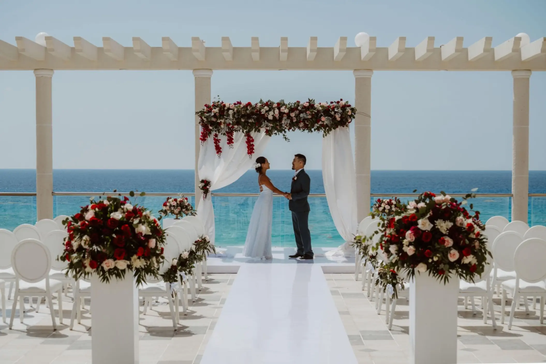 A bride and groom standing at the altar of a rooftop wedding ceremony with the Caribbean Sea as a backdrop.