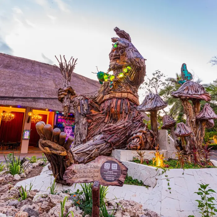 An impressive, large wooden art installation with green lights and butterflies at Sandos Caracol Eco Resort.